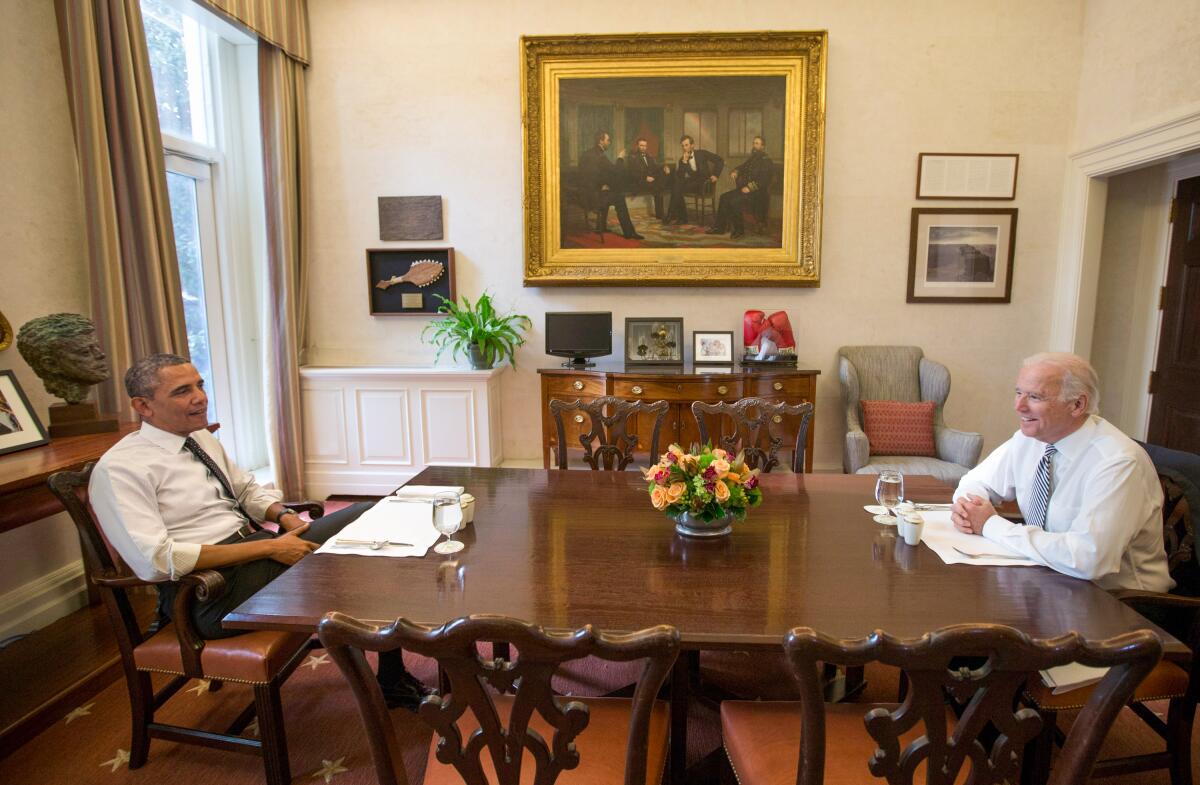 President Obama, left, and Vice President Joe Biden smile at a dining room table in the White House.