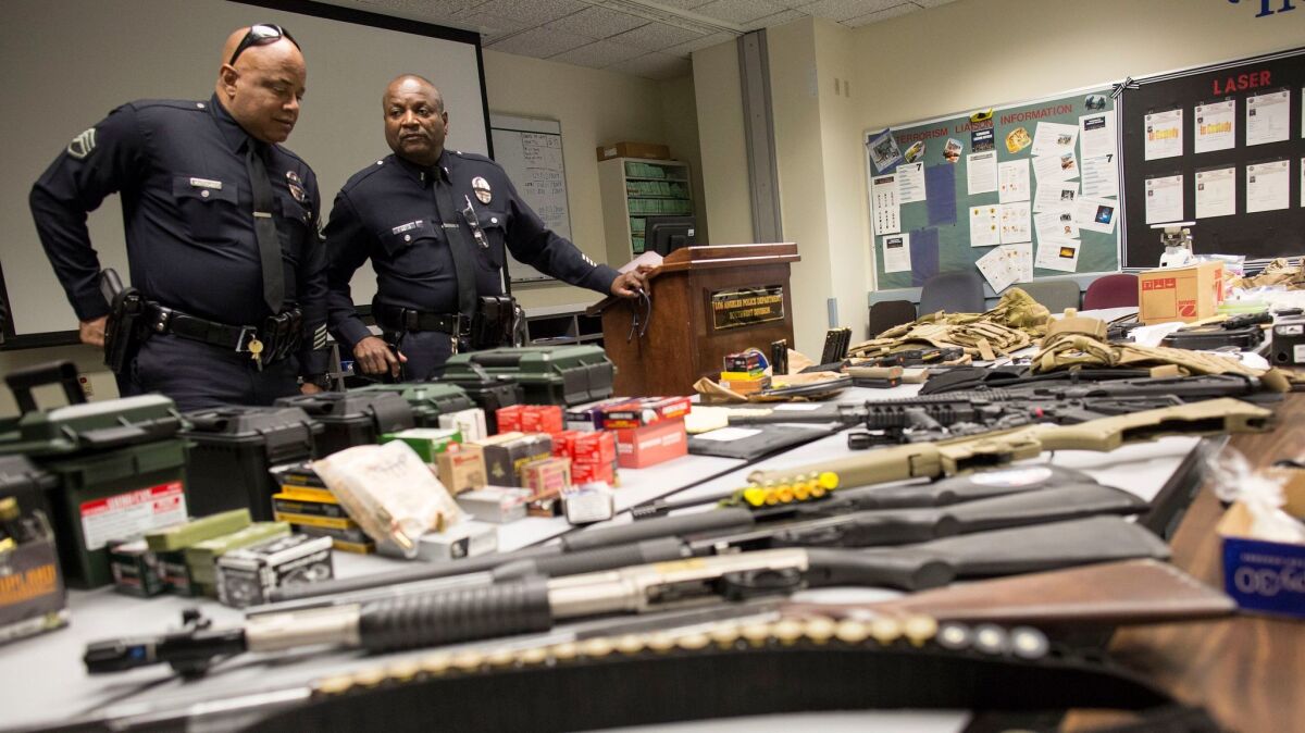 LAPD Sgt. Barry Montgomery, left, and Lt. Byron Roberts look over confiscated drugs, guns and cash after narcotics officers raided several locations early Thursday.