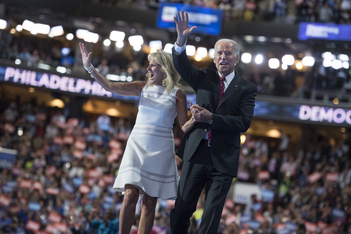 Jill and Joe Biden waving to a crowd of people in an arena