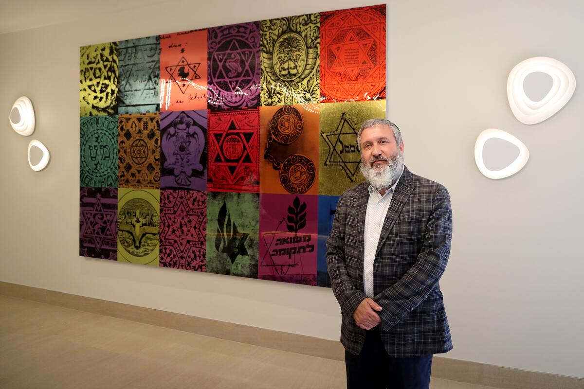 Rabbi Reuven Mintz stands in front of the History of the Star of David wall.