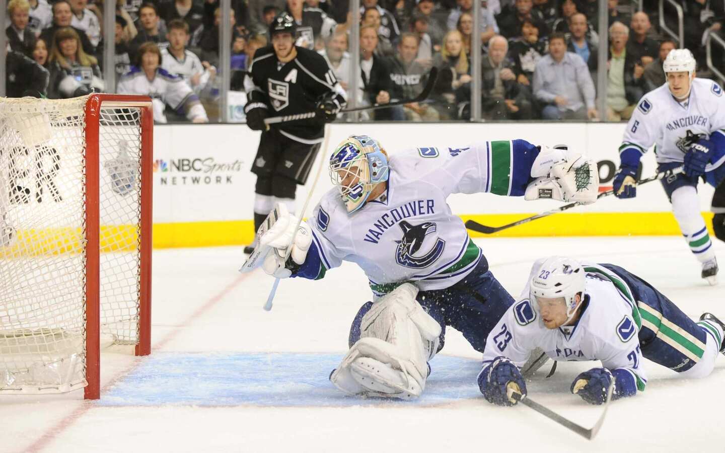 Canucks goaltender Cory Schneider and defenseman Alexander Edler watch as a shot by Dustin Brown (not pictured) goes into the goal in the third period Sunday night at Staples Center.