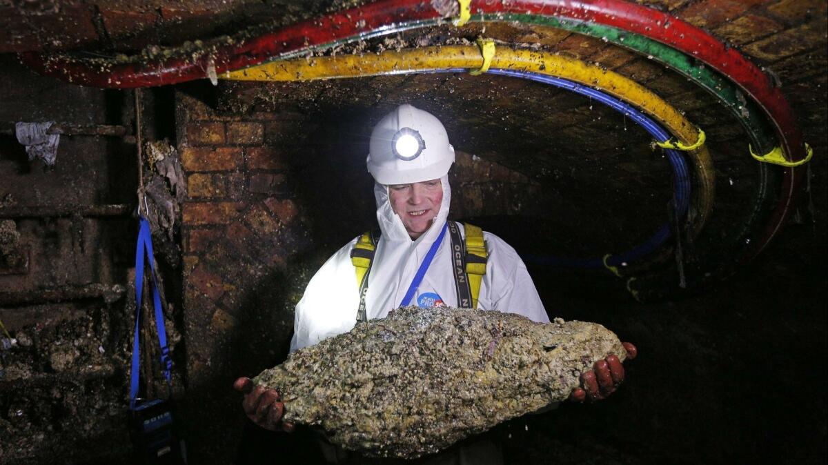A sewer worker in London holds a "fatberg," the nickname given to masses of wet wipes and other disposable items that can form in sewer lines and cause massive blockages.