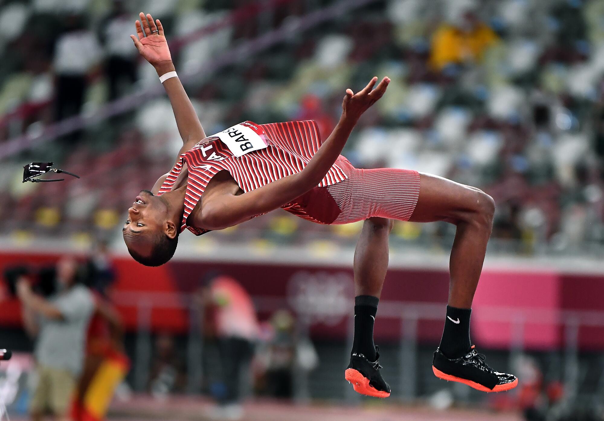 Qatar's Mutaz Barshim does a back flip as he loses his sunglasses