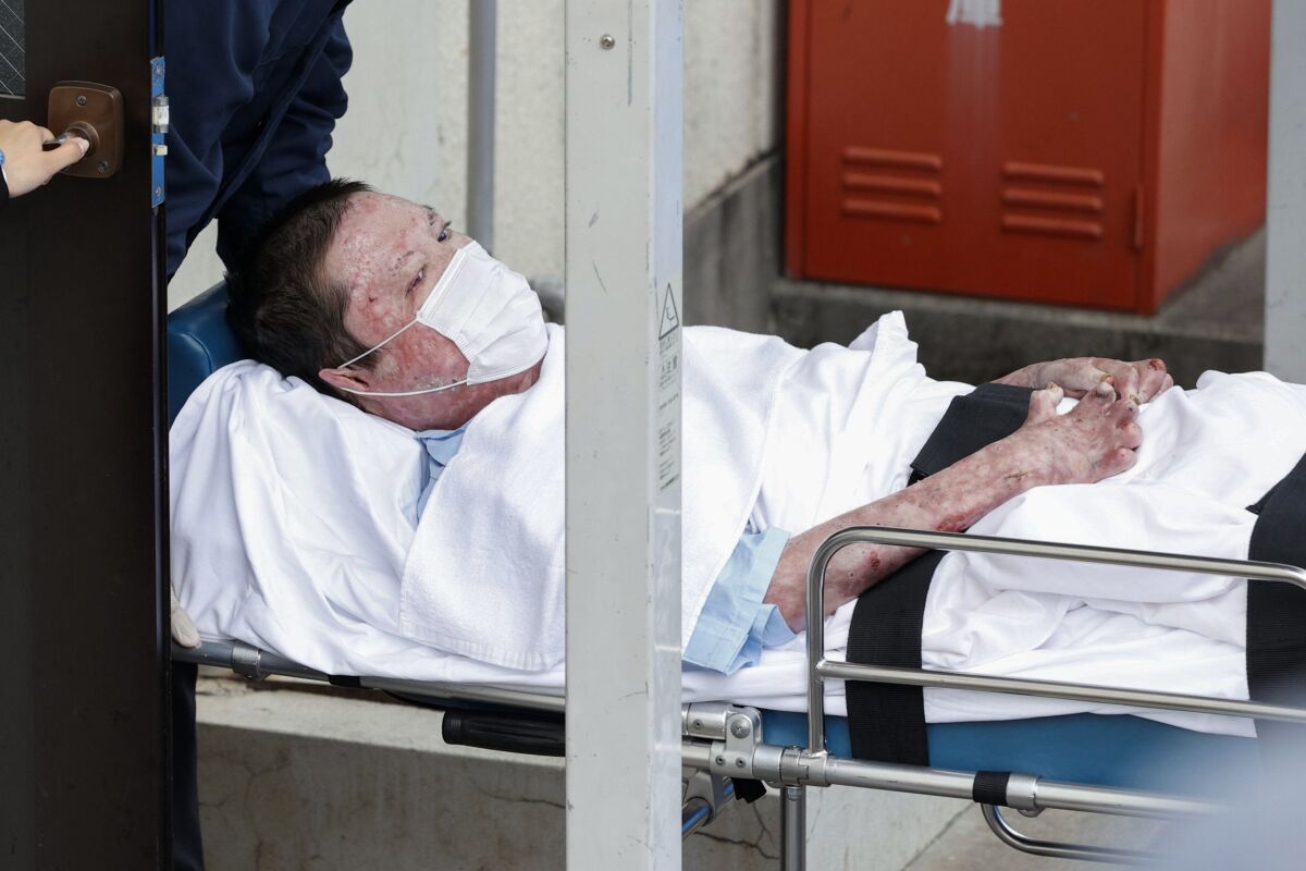 Shinji Aoba on a stretcher is carried to Fushimi police station May 27 after being arrested in Kyoto, western Japan.