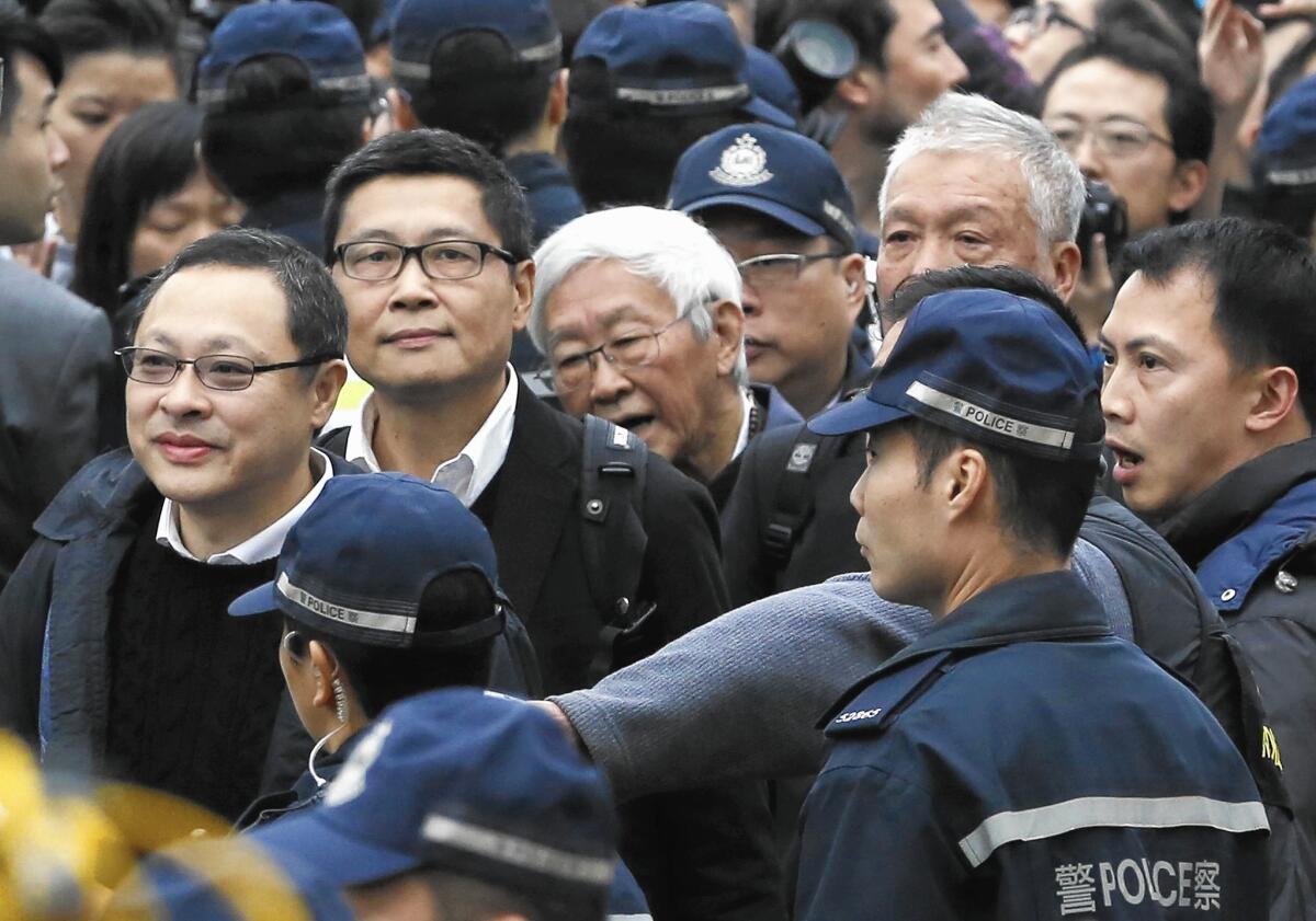 Hong Kong protest leaders, from left, Benny Tai, Chan Kin-man Joseph Zen and Chu Yiu-ming are escorted by officers to the police station after surrendering Dec. 3.