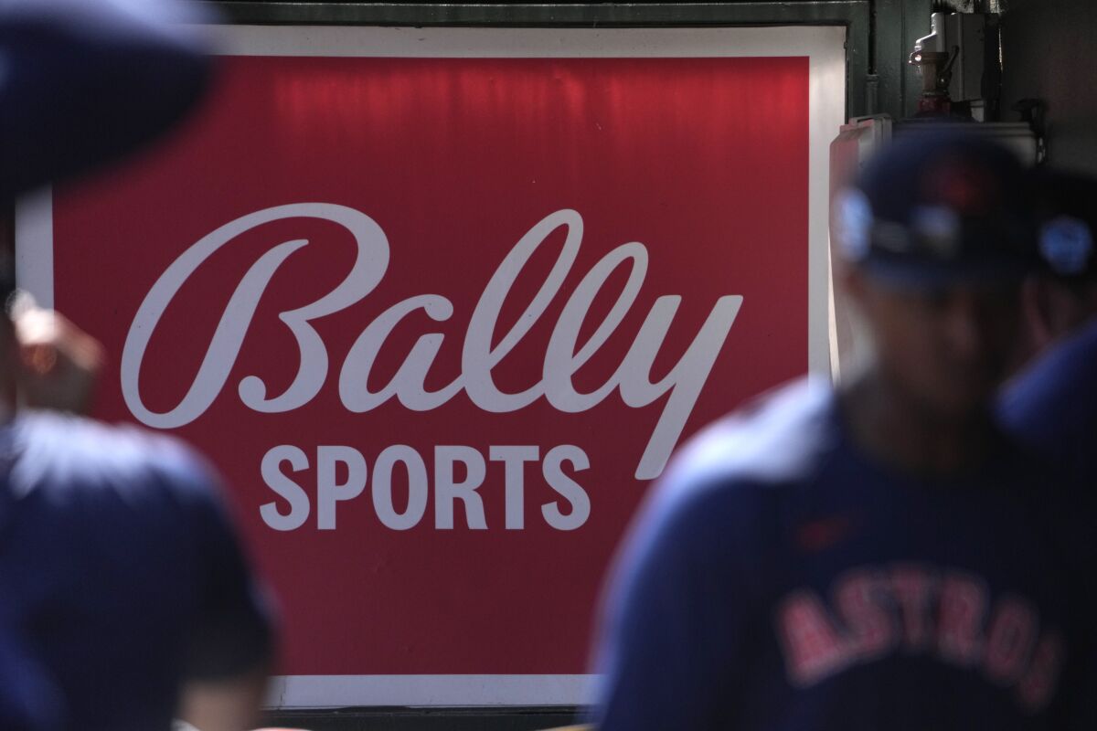 Les joueurs des Astros de Houston marchent devant un panneau Bally Sports dans la pirogue.