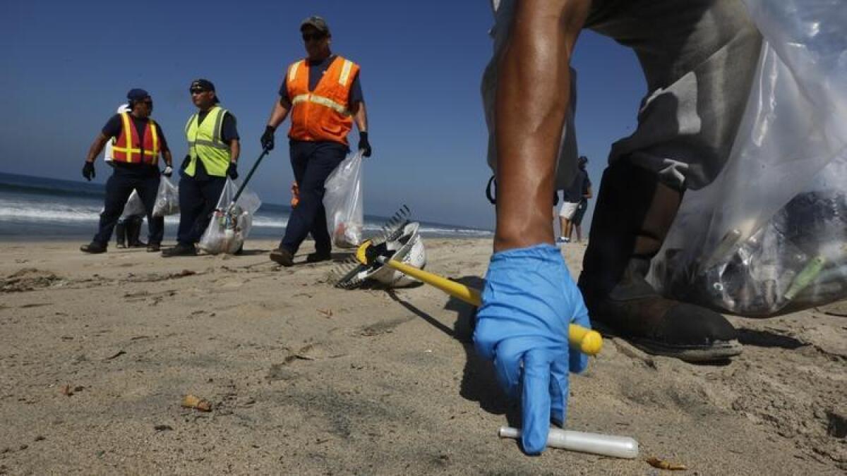 Los contratistas de limpieza de la ciudad de Los Ángeles recogen aplicadores de tampones que llegaron a tierra en Dockweiler State Beach en Playa del Rey, el 24 de septiembre de 2015.