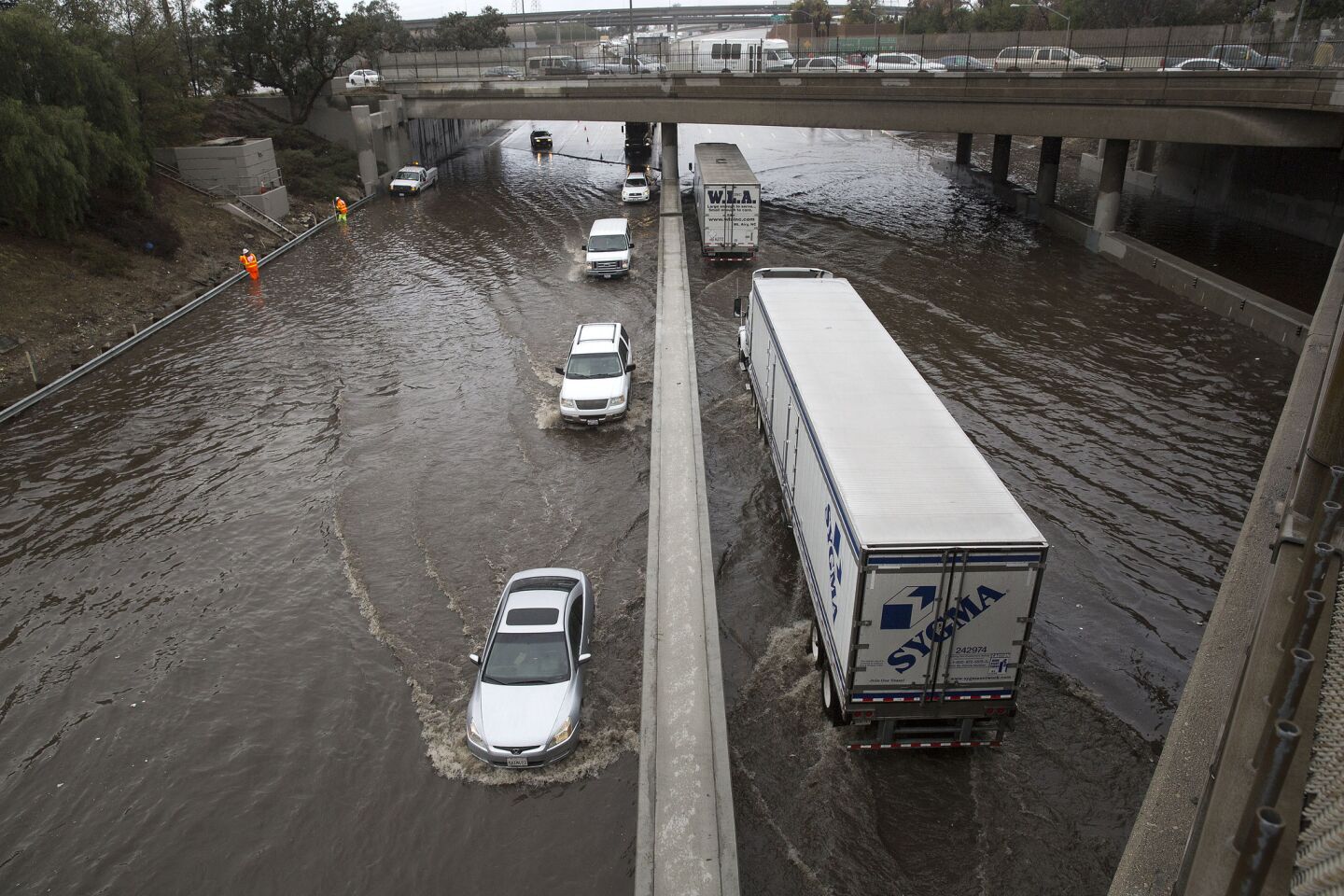 CHP officers limit traffic on a flooded Interstate 5 to one lane in each direction as Caltrans workers work to clear drains in Sun Valley, Calif.