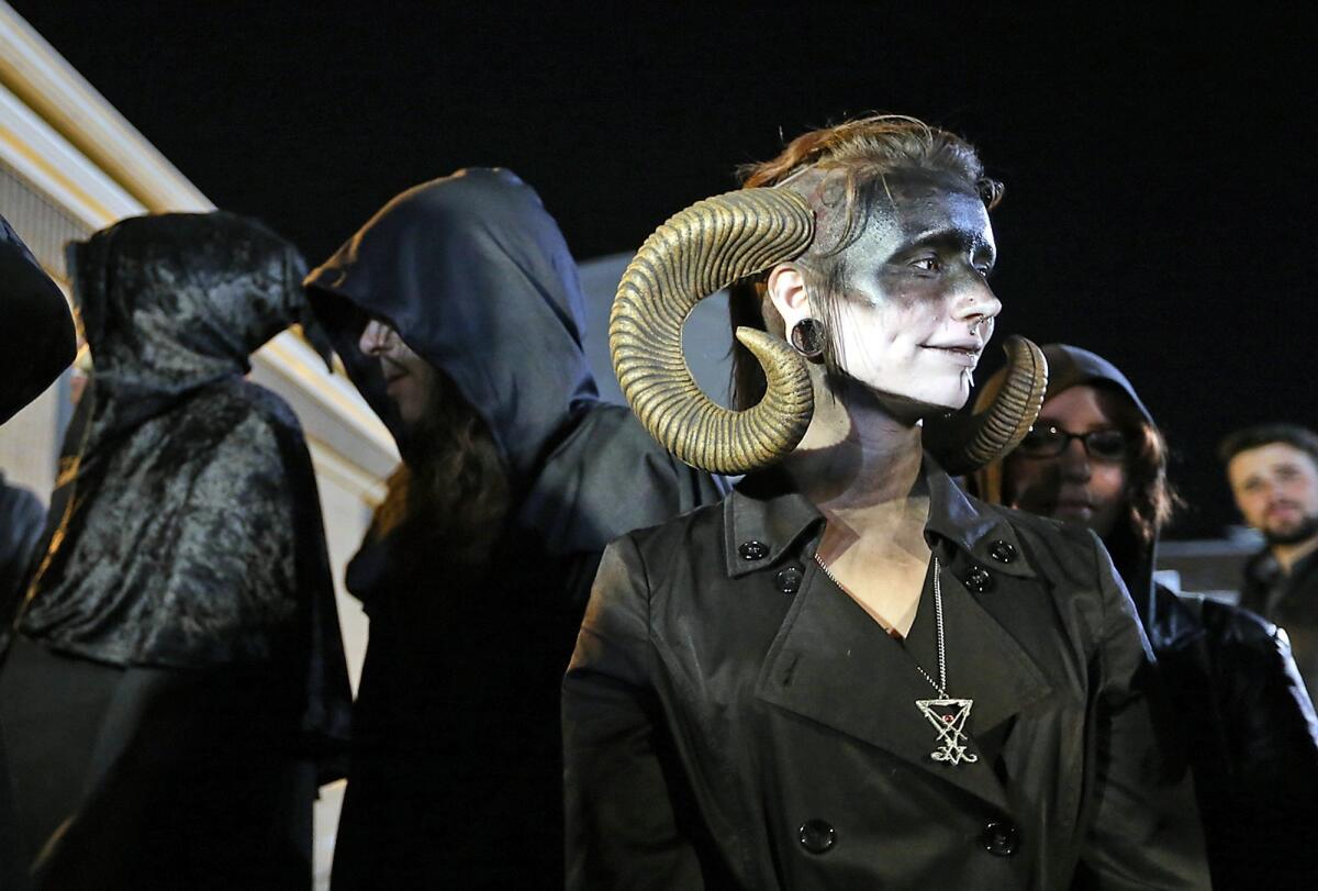 Satanic Temple of Seattle members gather outside a football game in Bremerton, Wash. in this file photo from Oct. 29, 2015. In Phoenix, Ariz., the City Council has now banned opening prayer at its meetings, prompted by a group of Satanists who sought to deliver an invocation of their own.