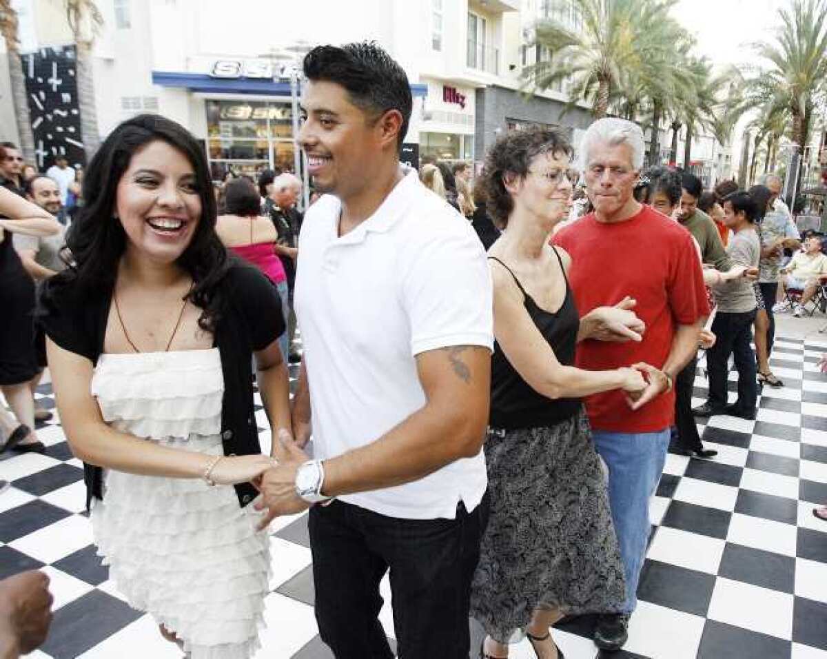 Nathaly Rafton and Jason Salinas, who are dance friends, learn how to salsa dance at the ninth annual 'Come Out and Dance Under the Stars' in Burbank.