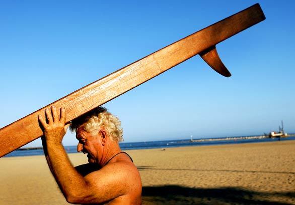 Then Sebasian Vizcaino sailed into Santa Barbara in the early 17th century to escape a storm on Saint Barbara's feast day. He named the bay and the land after the saint. Now These days, folks sail, kayak and ... well... fish the bay from a paddleboard. Bruce Wood of Santa Barbara hoists his homemade 14-foot mahogany paddleboard across West Beach and into the water to fish for halibut.