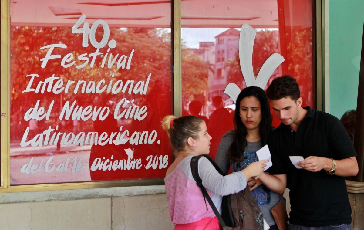 Varios jóvenes conversan al lado de un cartel que anuncia la 40 edición del Festival del Nuevo Cine Latinoamericano que se realiza ya en La Habana (Cuba).