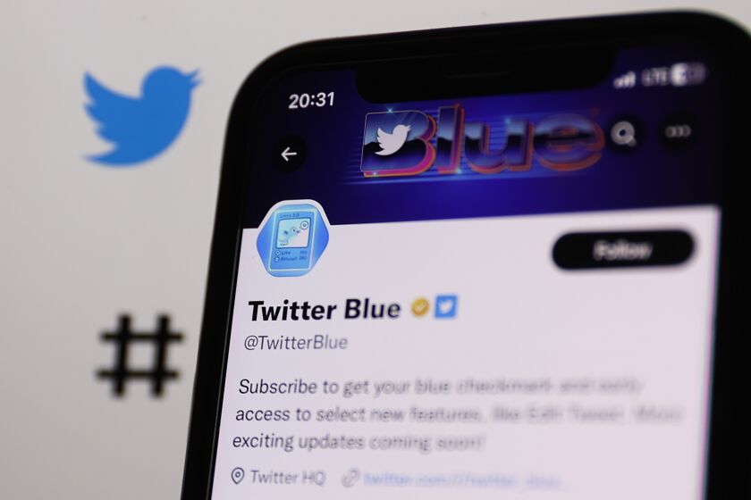 The golden checkmark on Twitter Blue account on Twitter displayed on a phone screen and Twitter website displayed on a screen in the background are seen in this illustration photo taken in Krakow, Poland on February 14, 2023 (Photo by Jakub Porzycki/NurPhoto via Getty Images)