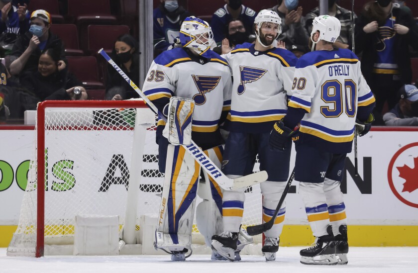 St. Louis Blues goalie Ville Husso, of Finland, from left to right, Robert Bortuzzo and Ryan O'Reilly celebrate after St. Louis defeated the Vancouver Canucks in an NHL hockey game, in Vancouver, British Columbia, Sunday, Jan. 23, 2022. (Darryl Dyck/The Canadian Press via AP)
