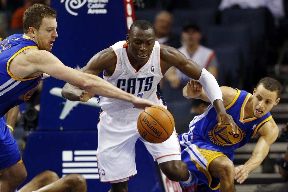 Golden State forward David Lee, left, and guard Stephen Curry chase after a loose ball with Charlotte Bobcats center Bismack Biyombo.