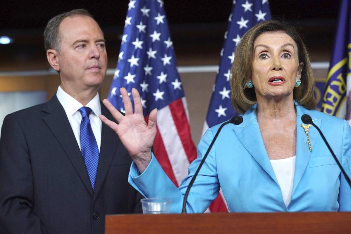 A woman speaks at a lectern as a man on her right watches.