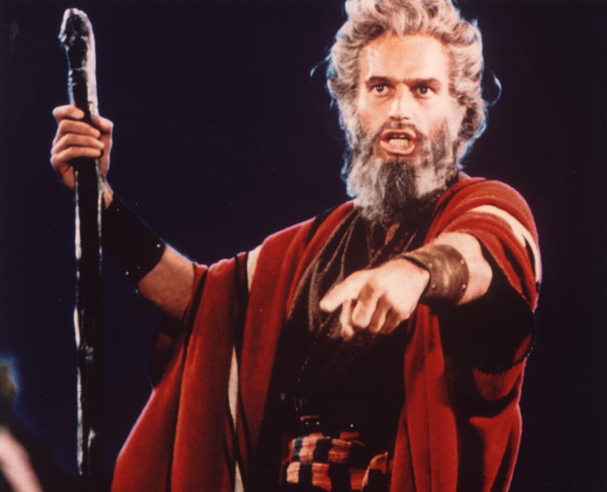 Charlton Heston speaks while pointing and holding a staff in a scene from “The Ten Commandments”