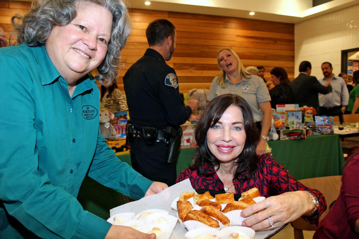 Porto’s co-owner Betty Porto serves Cuban sweets to Pamela Spiszman at the Glendale Latino Assn.'s toy drive mixer. 