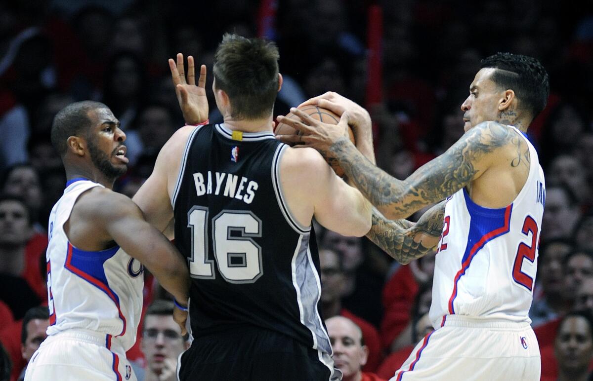 Clippers point guard Chris Paul, left, and forward Matt Barnes, right, try to strip the ball from Spurs center Aron Baynes in Game 1.