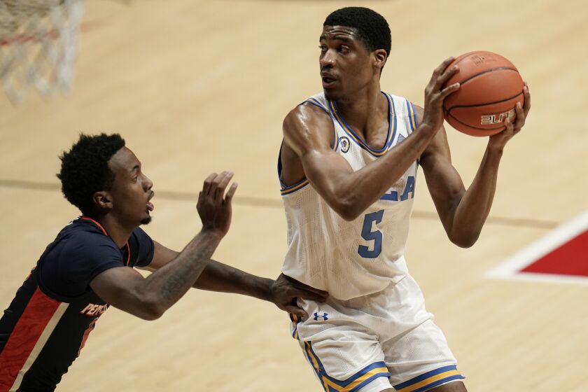 UCLA guard Chris Smith (5) looks to pass as Pepperdine guard Darryl Polk Jr. defends during the first half of an NCAA college basketball game Friday, Nov. 27, 2020, in San Diego. (AP Photo/Gregory Bull)