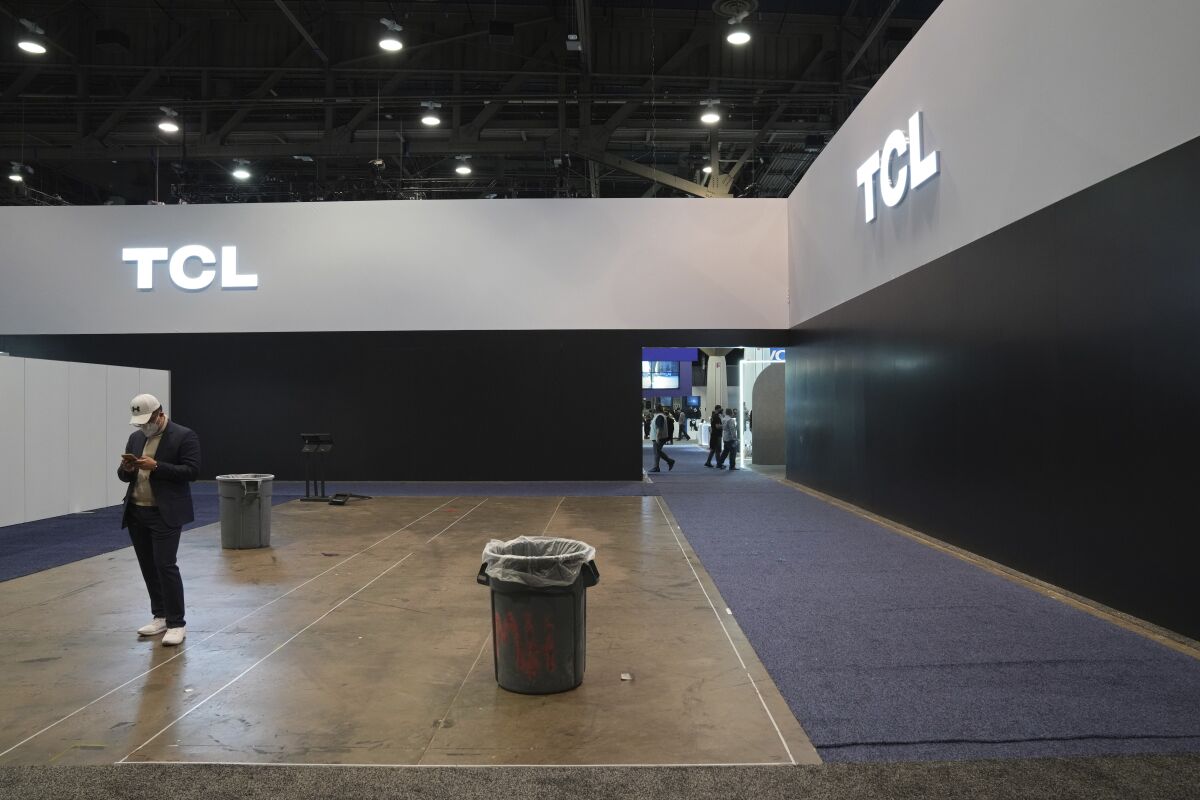 An attendee stands in an empty booth area near the TCL booth during the CES tech show Thursday, Jan. 6, 2022, in Las Vegas. (AP Photo/Joe Buglewicz)