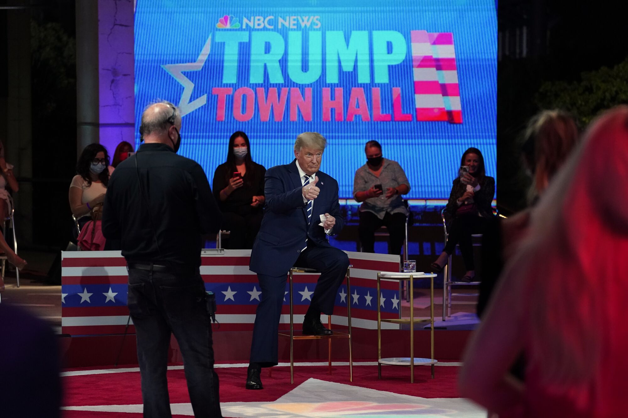 President Trump gives a thumbs up on stage in front of a wall that says NBC News Trump town hall