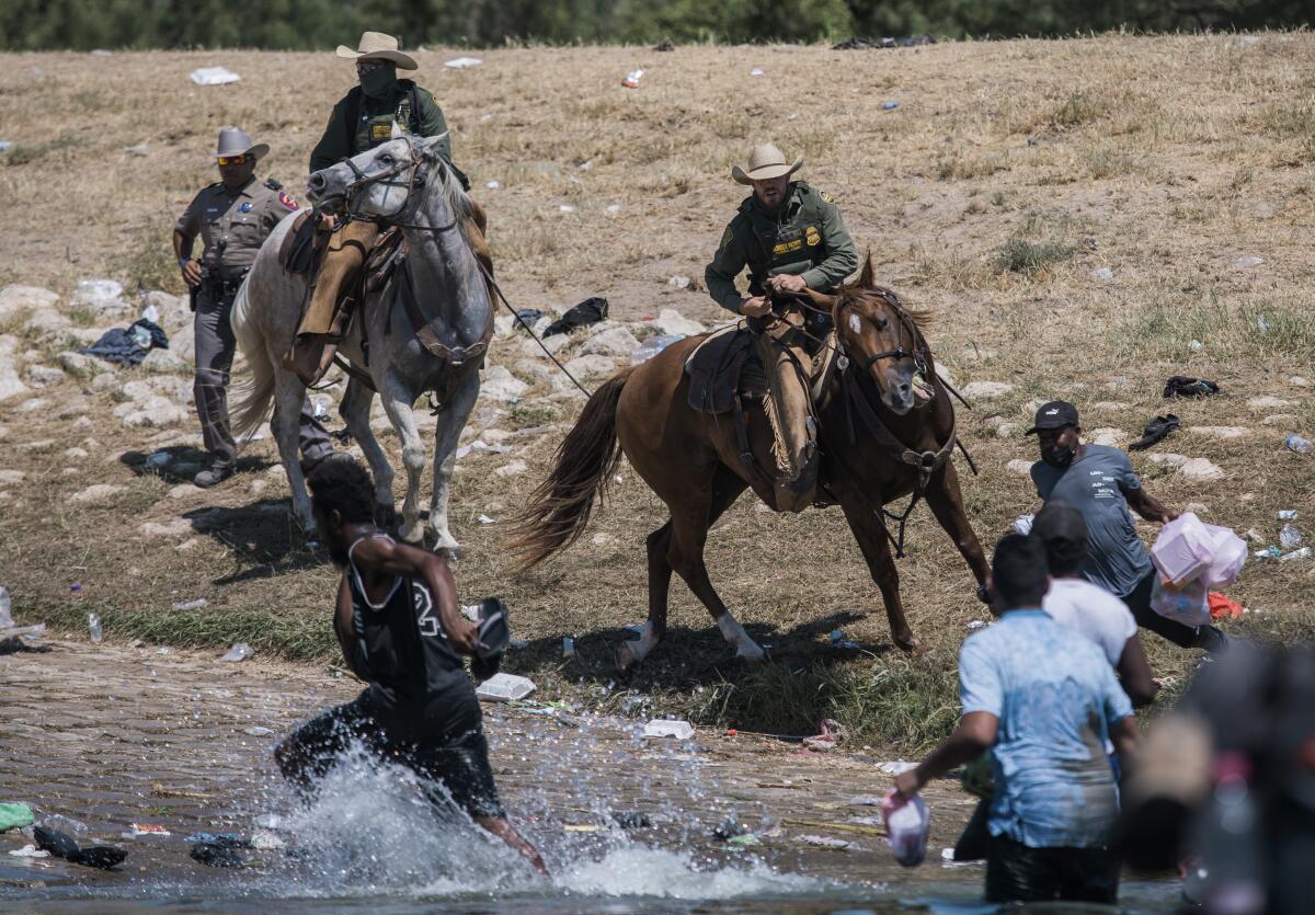Border Patrol officers on horseback attempt to contain migrants as they cross the Rio Grande into Del Rio, Texas
