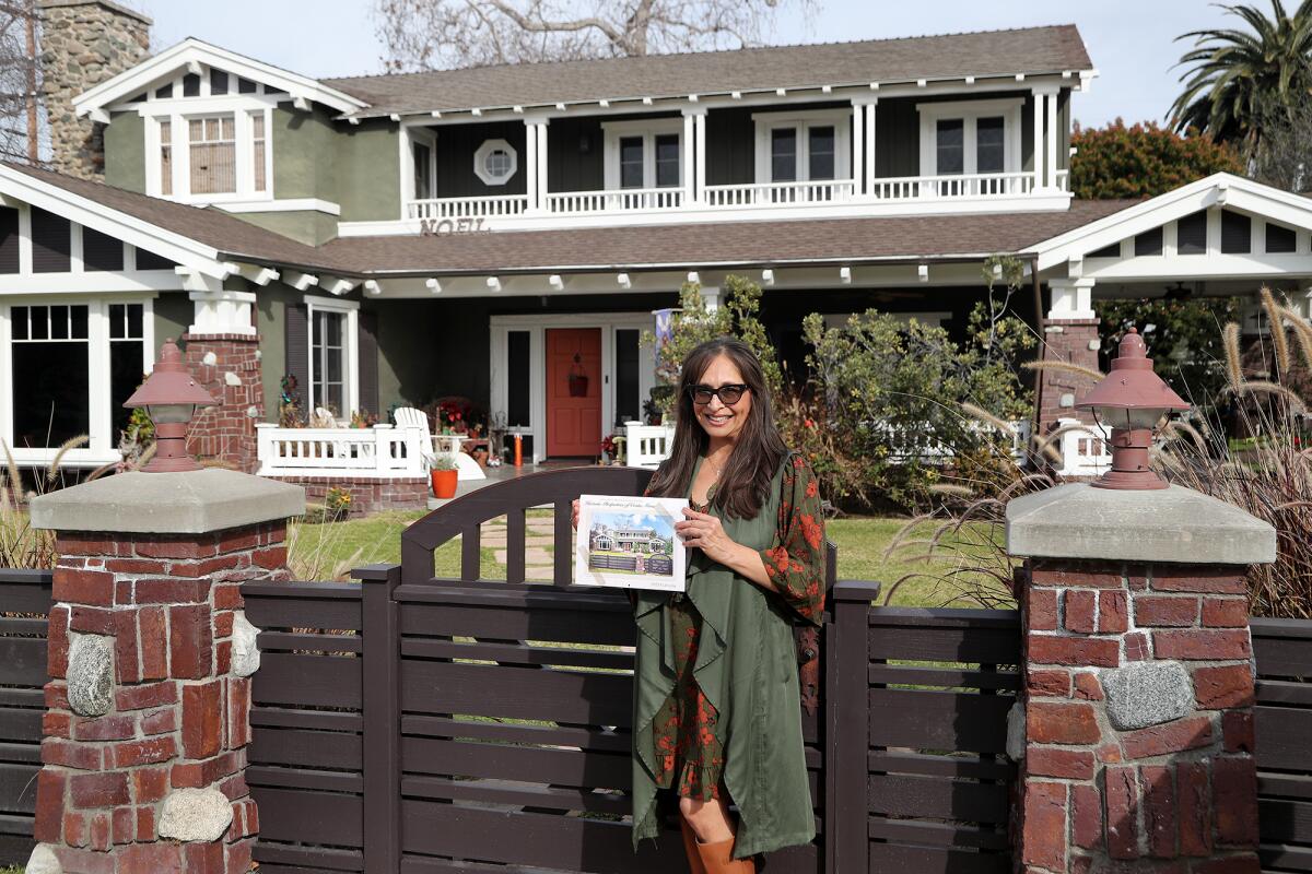 Realtor Renee Pina holds a second edition calendar of historic Costa Mesa homes outside 200 Magnolia St. in Costa Mesa.
