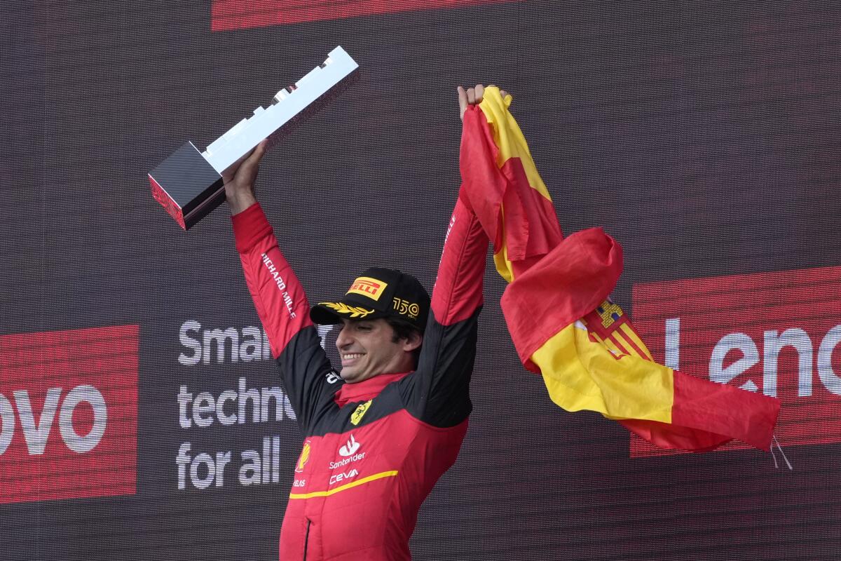 A man holds a trophy and a Spanish flag aloft.