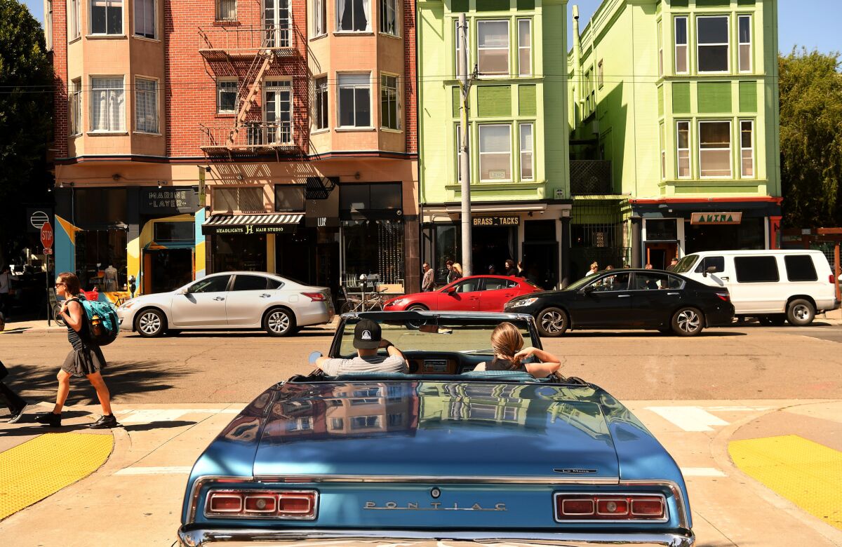 A couple drives their car through the Hayes Valley area of San Francisco.
