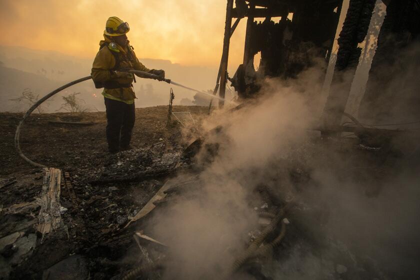 LOS ANGELES, CALIF. -- MONDAY, OCTOBER 28, 2019: A LA City firefighter keeps down flames at a burned home in the 1100 block of Tigertail Rd. in the Brentwood Heights neighborhood of Los Angeles, Calif., on Oct. 28, 2019. (Brian van der Brug / Los Angeles Times)
