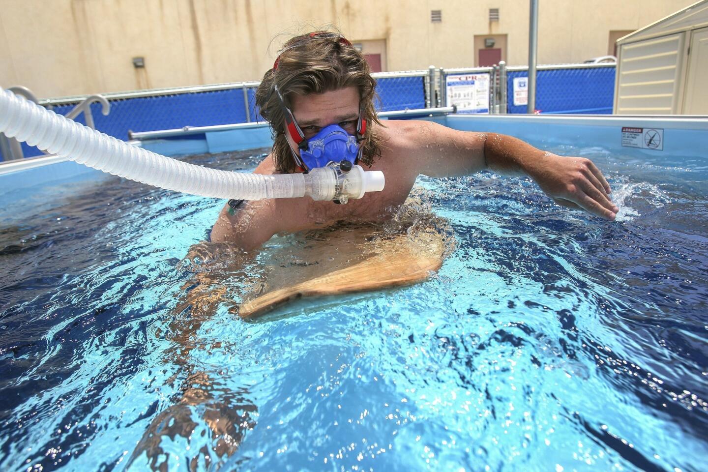 Kinesiology student Cody Cuchna, 24, paddles a surfboard while wearing a mask, to measure oxygen consumption, as he and other students demonstrate collecting physical measurements while paddling a surfboard in a swim flume.