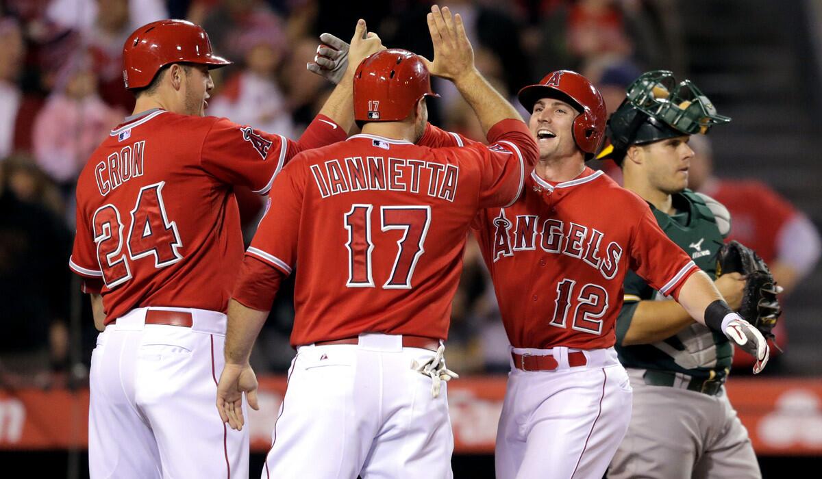 Angels second baseman Johnny Giavotella, right, is greeted at home plate by teammates C.J. Cron, left, and Chris Iannetta after hitting a 3-run home run during a 14-1 victory over the Oakland Athletics at Angel Stadium on Tuesday.
