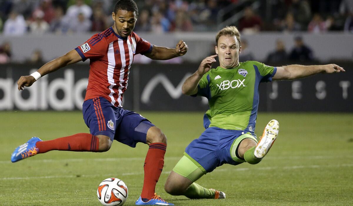 Chivas USA forward Luke Moore fires a shot against a diving Sounder defender Chad Marshall during a game last month.