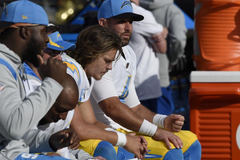 Los Angeles Chargers quarterbacks Justin Herbert, center, and Chase Daniel, right, sit on the bench with teammates during the second half of an NFL football game against the Baltimore Ravens, Sunday, Oct. 17, 2021, in Baltimore. The Ravens won 34-6. (AP Photo/Gail Burton)