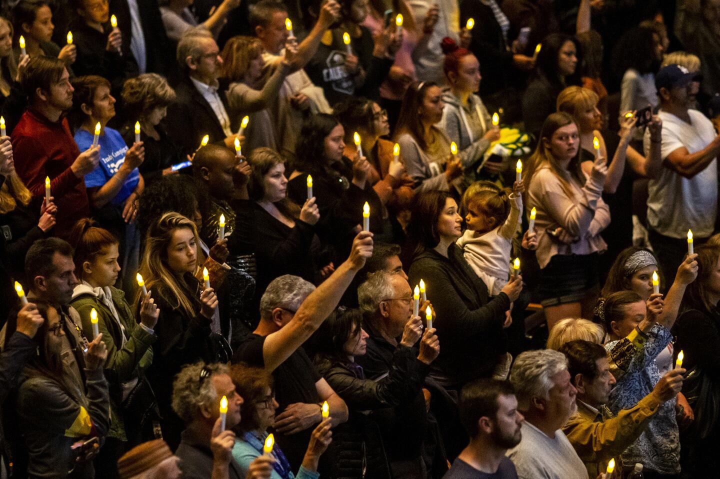 People in the Fred Kavli Theater raise battery-powered candles at a vigil for victims of the Borderline Bar and Grill shooting.