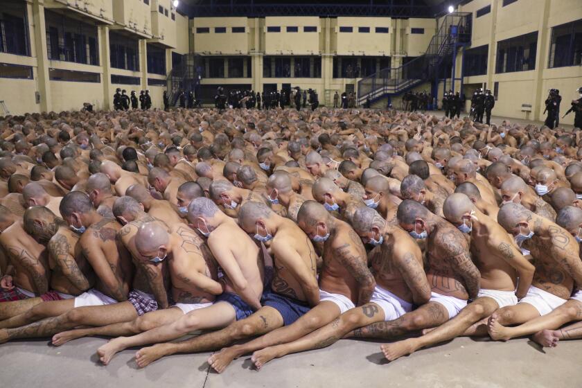 In this photo released by El Salvador Presidency Press Office, inmates are lined up during a security operation under the watch of police, everyone wearing masks as a precautions amid the spread of the new coronavirus, after President Nayib Bukele decreed maximum emergency in prisons that hold gang members, at the Izalco prison in San Salvador, El Salvador, Saturday, April 25, 2020. Bukele ordered the emergency the day after more than 20 people were killed throughout country that authorities said were ordered from prisons. (El Salvador President Press Office via AP)