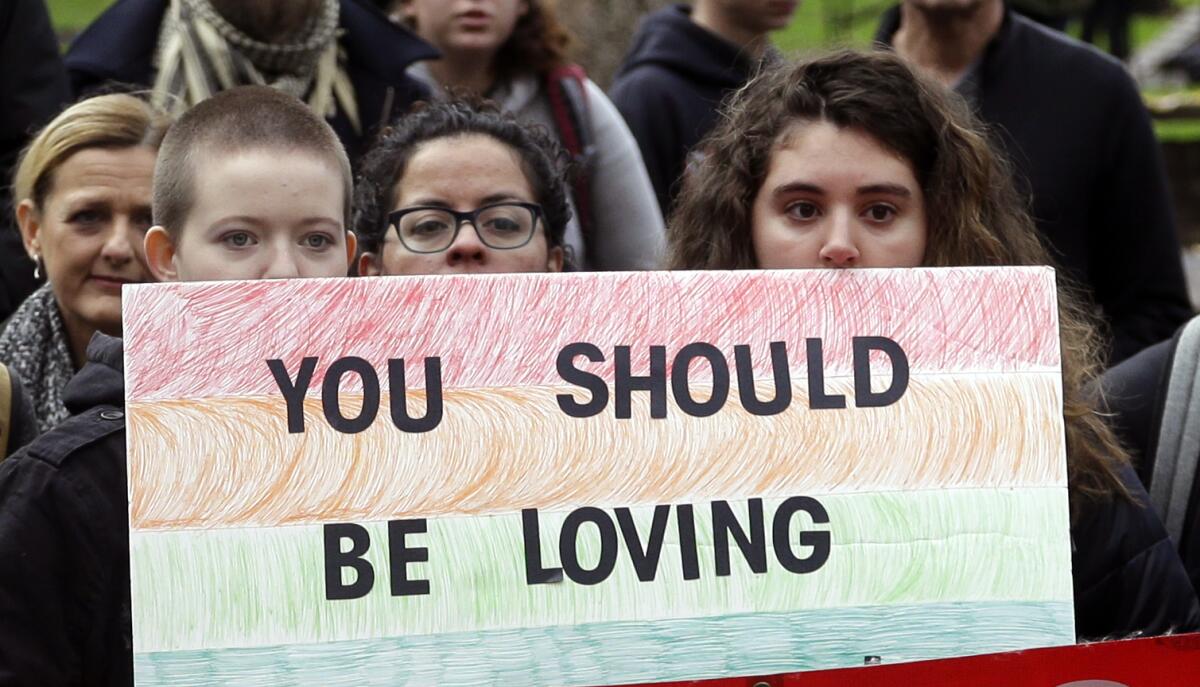 Protesters hold rainbow sign that reads "You should be loving" 