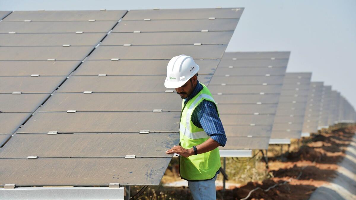 An Indian worker checks photovoltaic panels at the solar park in Pavagada