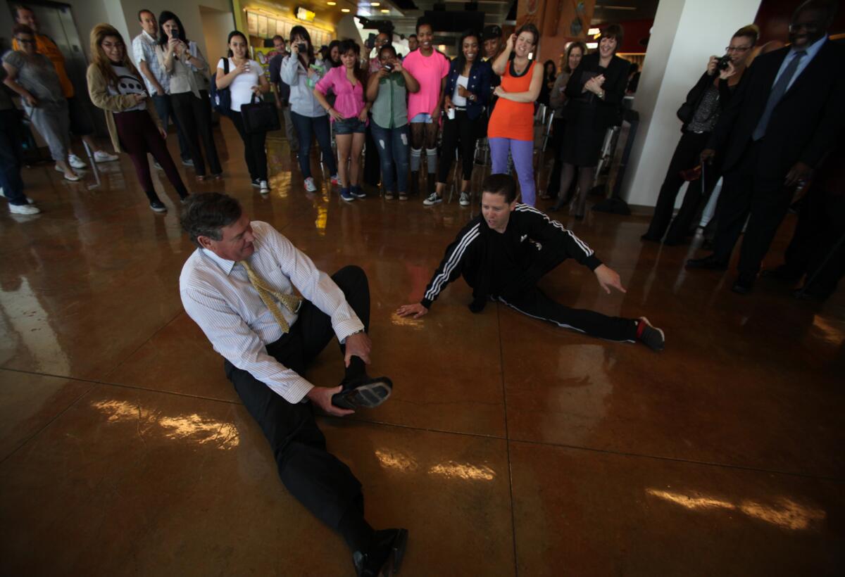Cal State Chancellor Timothy White, left, tours Cal State Dominguez Hills in Carson. After the students danced in a flash mob for him, he took off his shoes and tried to emulate the break dancing moves of senior Michael Amaton, 32, of Hermosa Beach, to the delight of the other students.