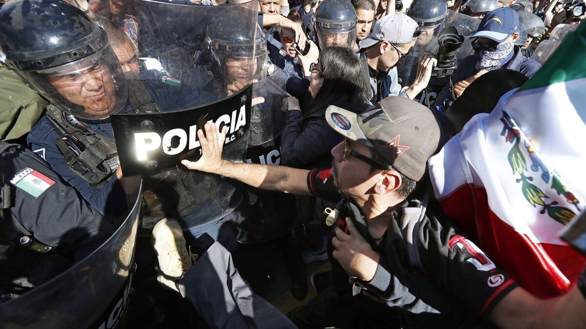 Protesters clash with police guarding a sports facility on Sunday in Tijuana, where more than 2,000 Central American migrants are sheltered.
