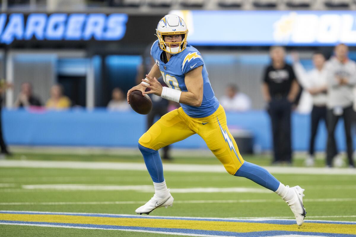 Chargers quarterback Justin Herbert runs with the ball against the Broncos in the first half.