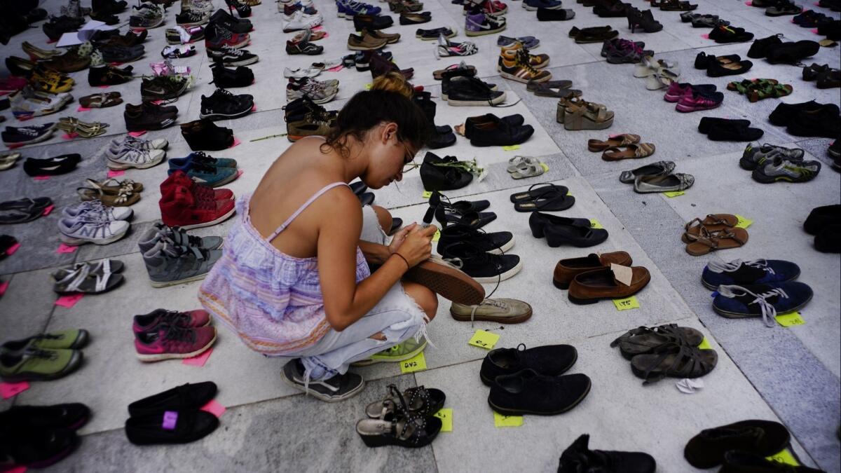 A woman adds shoes to a memorial display representing hurricane victims at the Puerto Rican capitol.