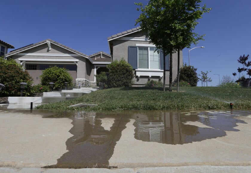 Water flows down a sidewalk from water sprinklers running at a home in Rancho Cordova in 2015.