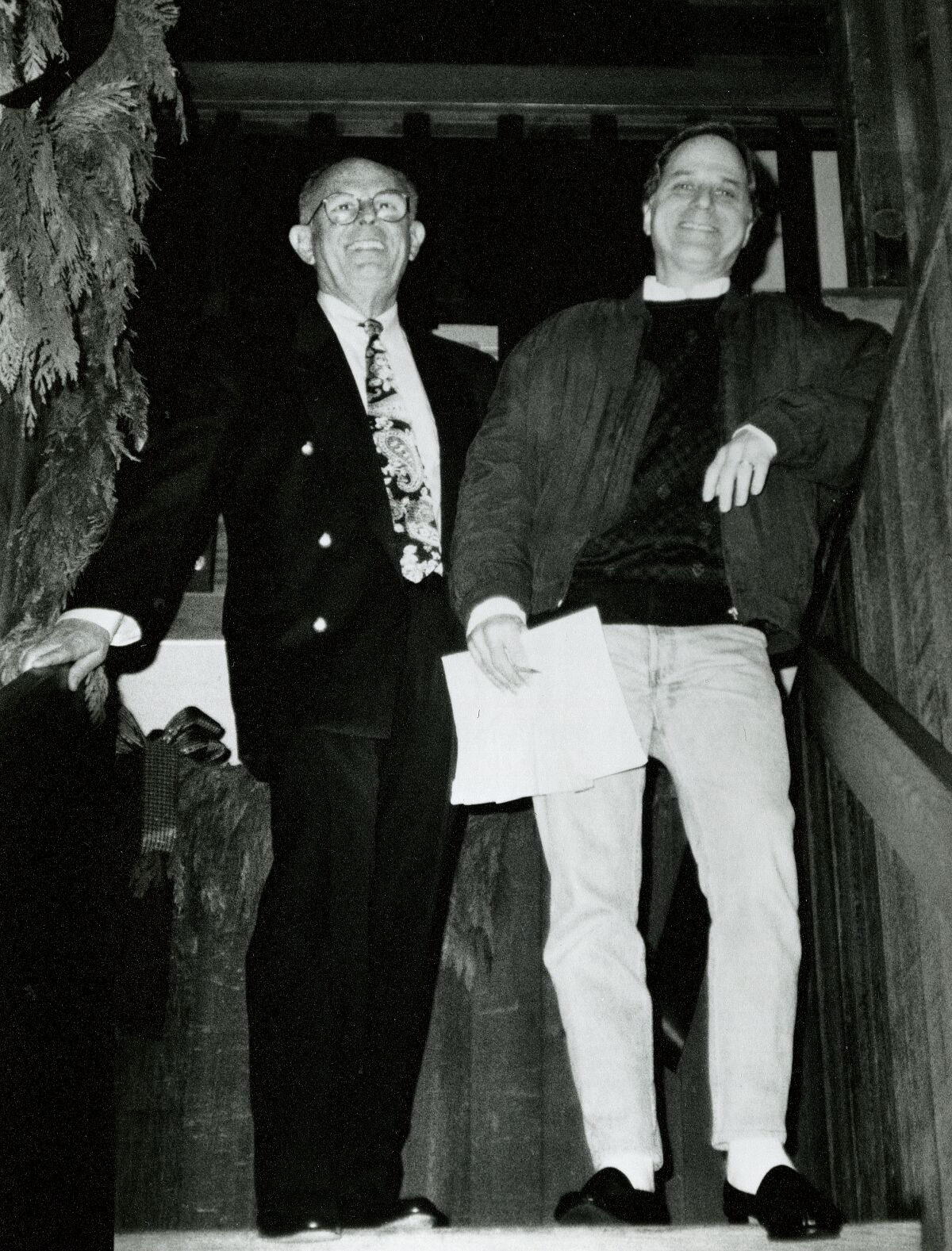 A black-and-white photo of two men standing at the top of a staircase.