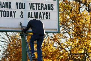 Ben Kroll, 17, of West Bend, puts his head down to watch his step as he climbs down a ladder to get more letters to complete the message for veterans outside of Bits N Pieces Floral Shoppe sign Thursday, Nov. 10, 2016 in West Bend, Wis.