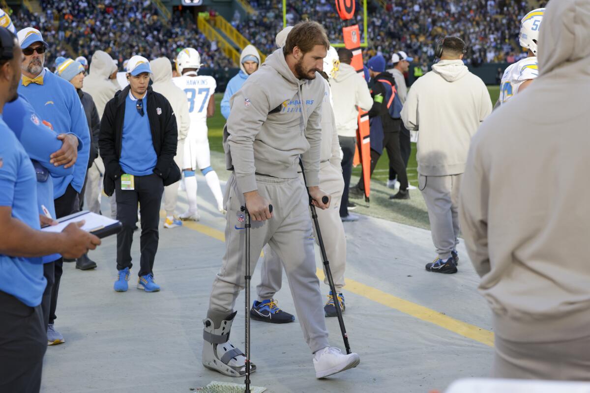 Chargers linebacker Joey Bosa walks with a boot and crutches on the sideline.