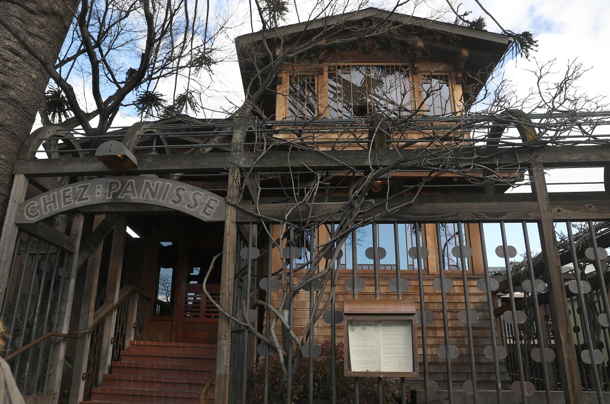 The exterior of Berkeley restaurant Chez Panisse, a wooden building behind a decorative metal fence.