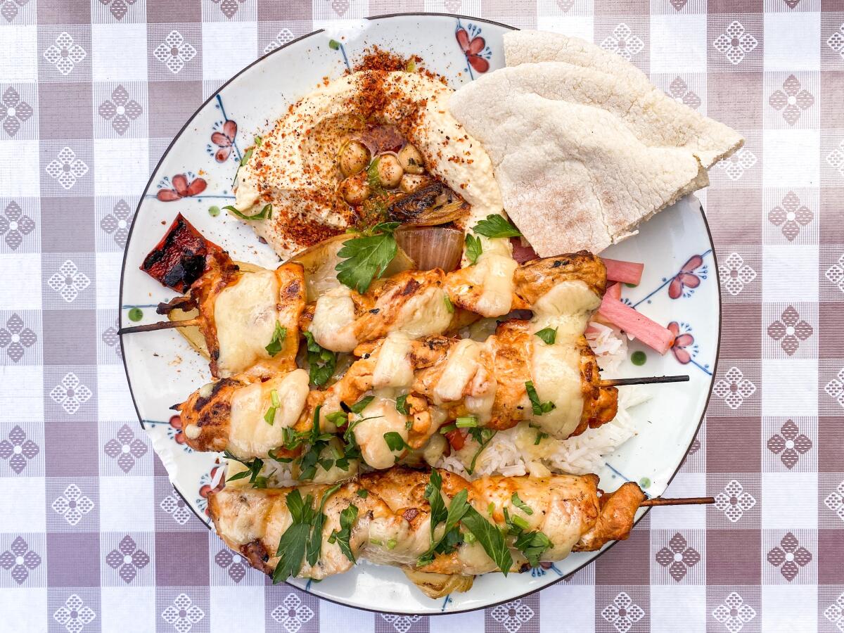 A plate with sauce and chicken on skewers.