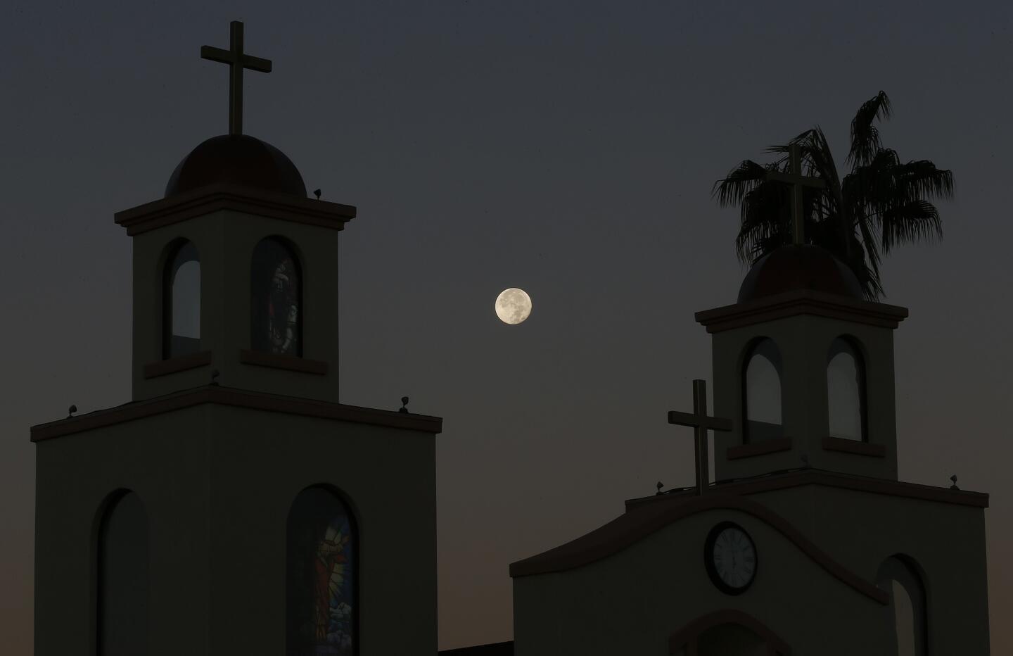 A supermoon descends over the Holy Family Catholic Church spires on Nov. 15, 2016, in Phoenix.